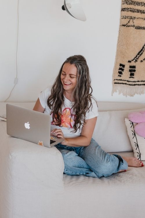 Steffi travaille à la création d'un site web écologique en souriant sur un coin de canapé